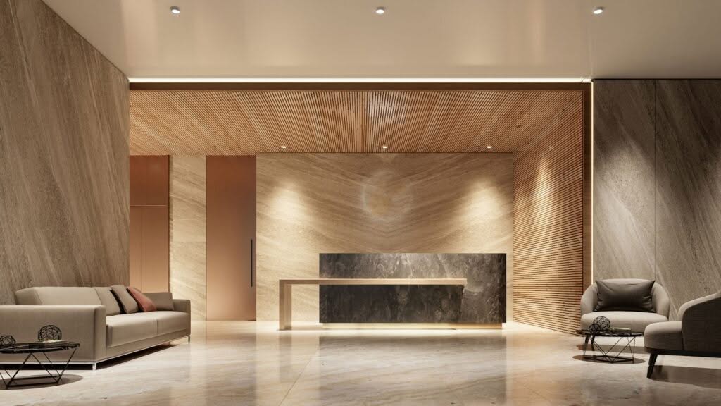 A modern, minimalist lobby showcases Commercial Interior Design in Weehawken, featuring neutral tones, marble floors, a sleek dark reception desk, beige sofas with pillows, round side tables, and textured wood and stone walls under elegant recessed lighting.